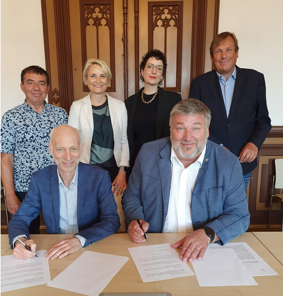 Zwei Männer unterschreiben die Kooperation zwischen City-Management-Verband Ost und Aktionskreis City- und Stadtmarketing Bayern